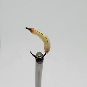 May include: A white and brown fly fishing lure with a curved hook.