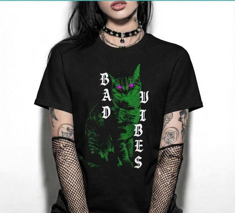 Front view of a person in a black graphic t-shirt with a green cat and the text Bad Vibes.