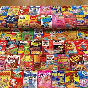 May include: A multi-colored fabric featuring a repeating grid pattern of vintage cereal box designs. The print includes various iconic breakfast cereal brands, cartoon mascots, and colorful logos arranged in rows across the entire surface of the textile.