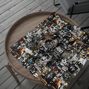 A small gift wrapped in black and white Misfits-themed paper with a brown bow, sitting on a larger sheet of the same paper on a wooden table.