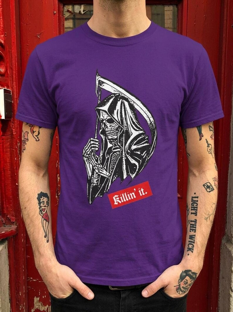 A person wearing a purple t-shirt featuring a grim reaper illustration and red text.