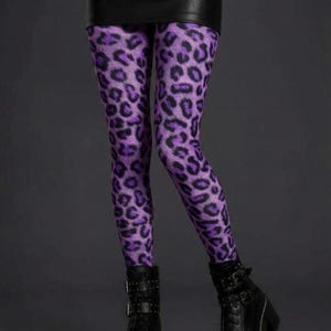 A person wearing purple and black leopard print leggings, a black miniskirt, and black platform combat boots.