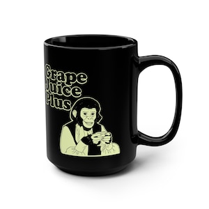 May include: Black ceramic mug with the text "Grape Juice Plus" in a retro font. A cartoon chimpanzee is depicted holding a cup. The mug has a large handle and a glossy finish.