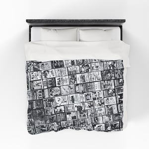 An overhead view of a bed with white sheets and a black and white Misfits blanket, featuring a collage of band art.