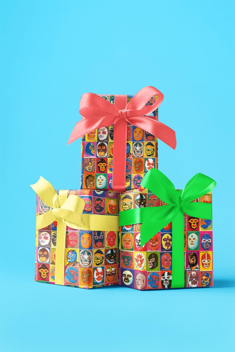 May include: Three gift boxes wrapped in colorful paper with images of wrestling masks. The top box is tied with a red ribbon, the middle box is tied with a yellow ribbon, and the bottom box is tied with a green ribbon.