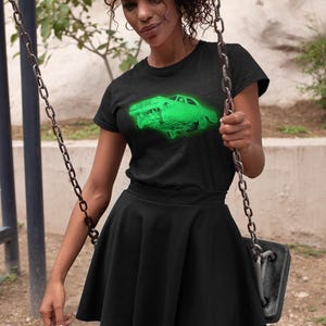 May include: A black short-sleeved t-shirt featuring a vibrant neon green graphic of a classic car on the chest, paired with a matching black high-waisted skater skirt that has a flared silhouette and a smooth, solid fabric finish.