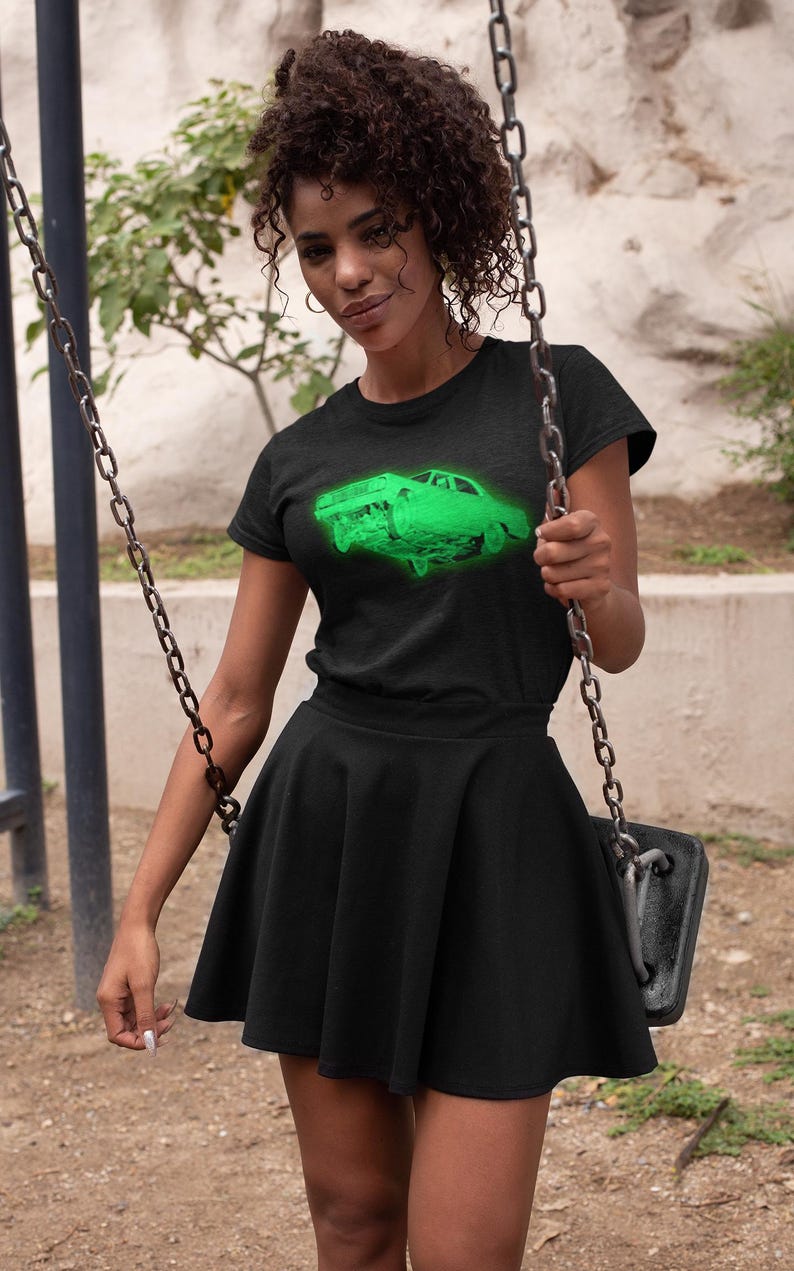 May include: A black short-sleeved t-shirt featuring a vibrant neon green graphic of a classic car on the chest, paired with a matching black high-waisted skater skirt that has a flared silhouette and a smooth, solid fabric finish.