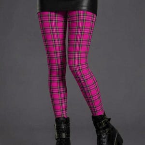 A person wearing pink plaid leggings with yellow and black lines, a black miniskirt, and black platform combat boots.