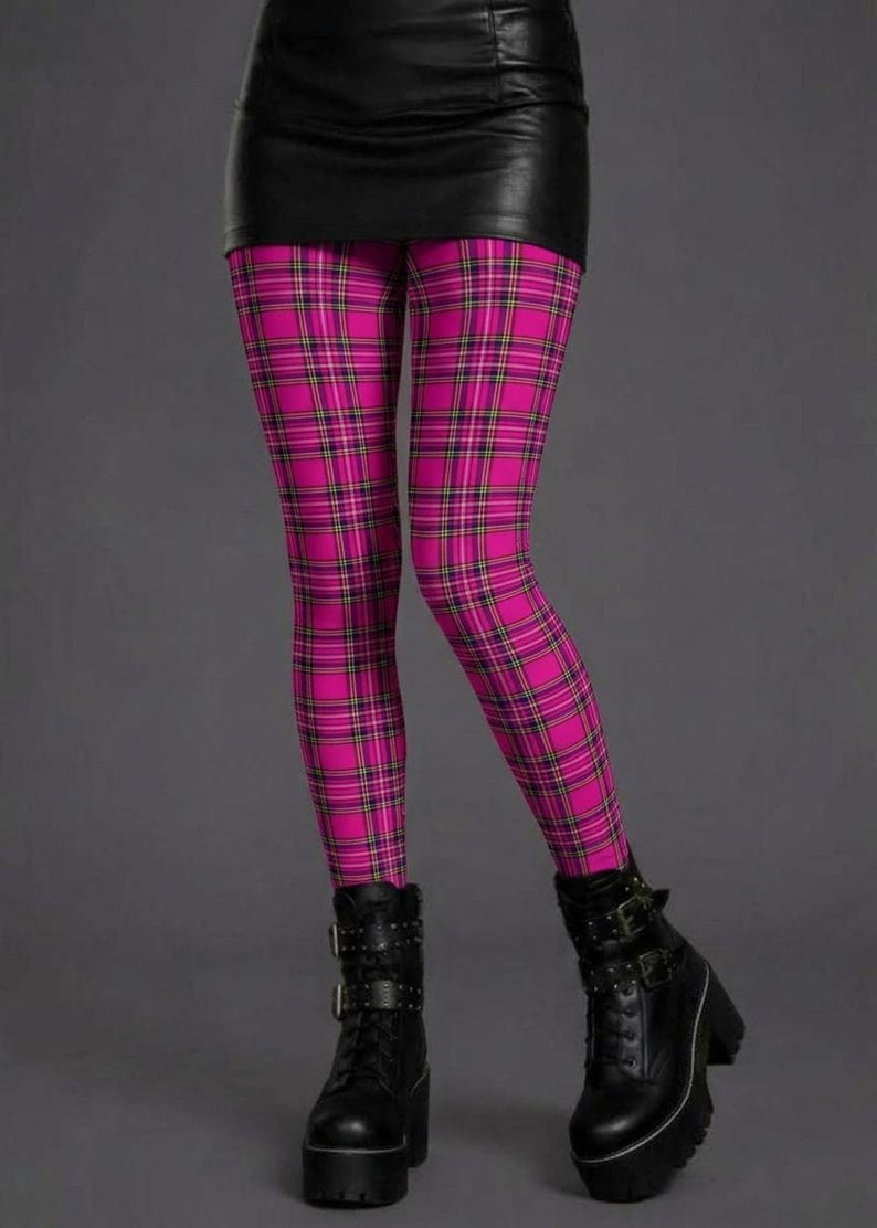 A person wearing pink plaid leggings with yellow and black lines, a black miniskirt, and black platform combat boots.