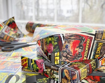 May include: Gift boxes wrapped in vintage horror film poster paper. The boxes are arranged on a table covered with the same paper, with scissors and a black ribbon nearby. The posters feature images of monsters and classic horror film titles.