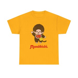 A gold-yellow short-sleeved t-shirt centered on a white background, featuring a Monchhichi graphic on the front.