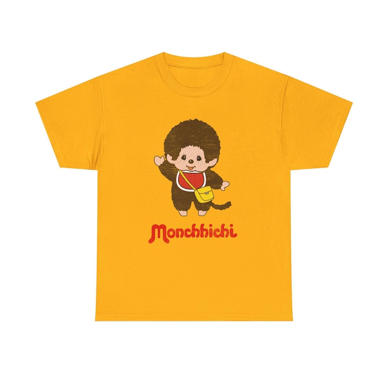 A gold-yellow short-sleeved t-shirt centered on a white background, featuring a Monchhichi graphic on the front.