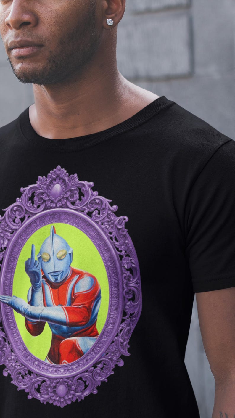 May include: Black t-shirt with a graphic of a retro superhero character giving the middle finger. The character is in red, blue, and silver, set against a lime green background within a purple ornate frame.