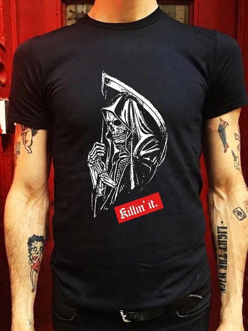 A person wearing a black t-shirt printed with a graphic of a grim reaper in a hood holding a scythe.