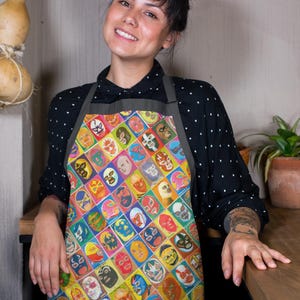 May include: A person wearing a black and white polka dot shirt with a green apron. The apron has a colorful pattern of wrestling masks.