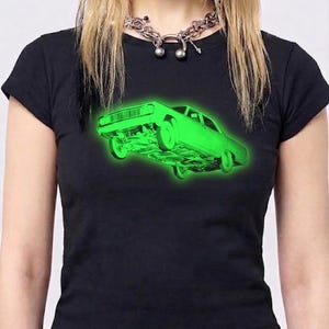 May include: A black short-sleeved t-shirt featuring a vibrant neon green graphic of a car floating in the center. The car illustration shows the underside and wheels in detail, creating a glowing effect against the dark fabric of the shirt.