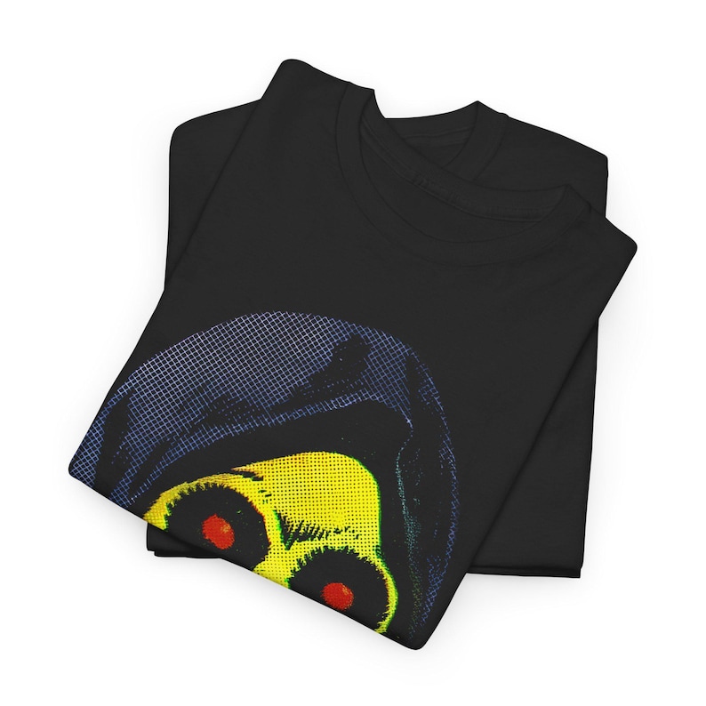 Two folded black t-shirts, with the top one showing a partial graphic of a yellow skull with red eyes in a blue hood.