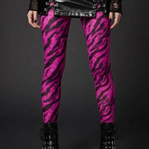 A person wearing pink and black tiger print leggings, a laced black leather skirt, and black platform boots.