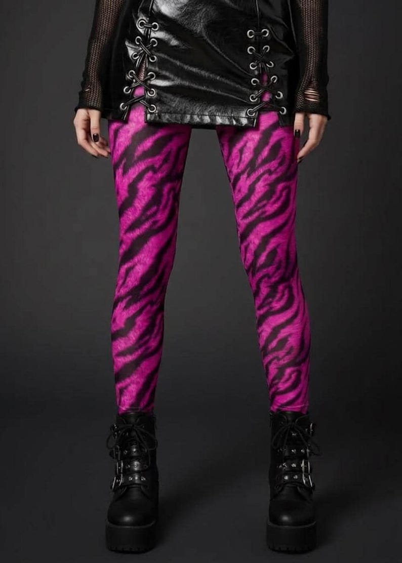 A person wearing pink and black tiger print leggings, a laced black leather skirt, and black platform boots.