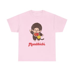 A light pink short-sleeved t-shirt displayed on a white background, featuring a cartoon monkey graphic and red Monchhichi text.