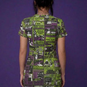 Back view of a person standing in the green and purple horror movie poster print t-shirt dress and fishnet stockings.