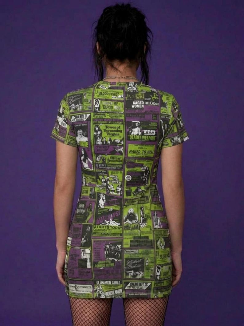 Back view of a person standing in the green and purple horror movie poster print t-shirt dress and fishnet stockings.