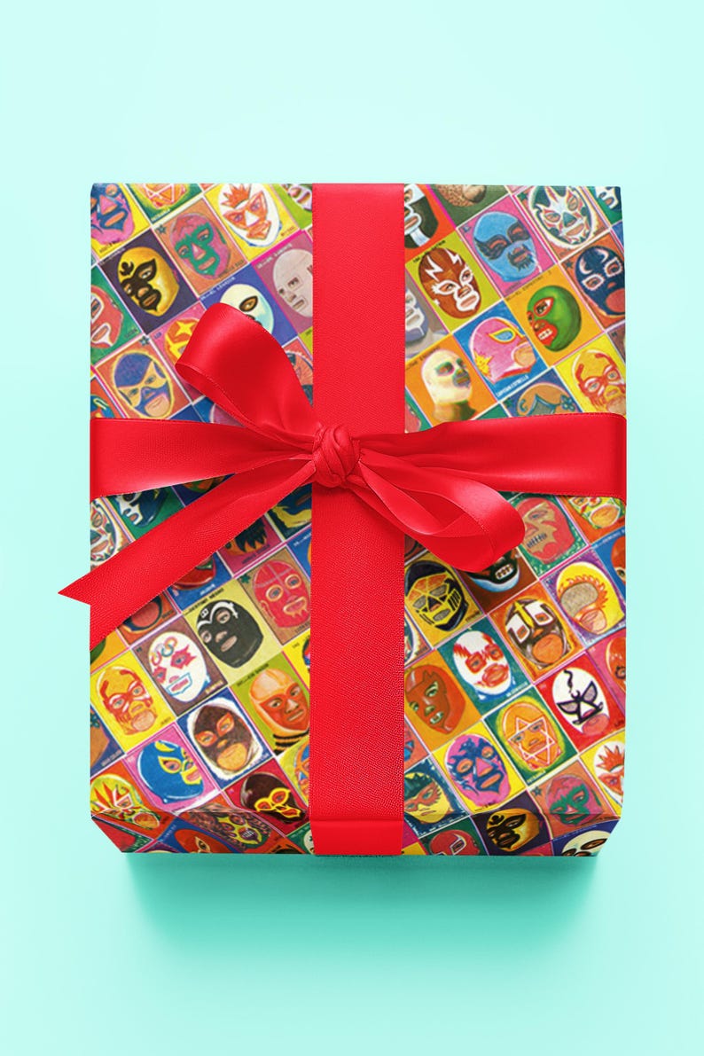 May include: A red ribbon tied around a gift box wrapped in colorful wrapping paper featuring a pattern of luchador wrestling masks.