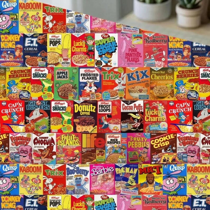May include: A multi-colored fabric featuring a repeating grid pattern of vintage cereal boxes. The design includes iconic brands such as Quisp, Kaboom, Trix, Lucky Charms, Super Sugar Crisp, Pink Panther Flakes, Donkey Kong, E.T., and Cap'n Crunch.