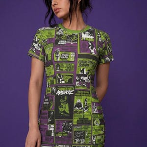 Close-up of a person wearing the horror movie poster t-shirt dress and fishnet stockings against a purple background.