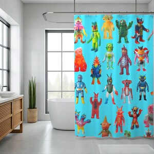 Puede incluir: Una cortina de ducha turquesa con un patrón repetido de juguetes monstruosos coloridos de estilo vintage. Los juguetes son de varios colores, incluyendo rojo, verde, amarillo y azul. La cortina cuelga en un baño moderno con una bañera blanca y un tocador de madera.
