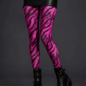 A person wearing vibrant pink and black tiger stripe leggings, a black miniskirt, and black platform combat boots.