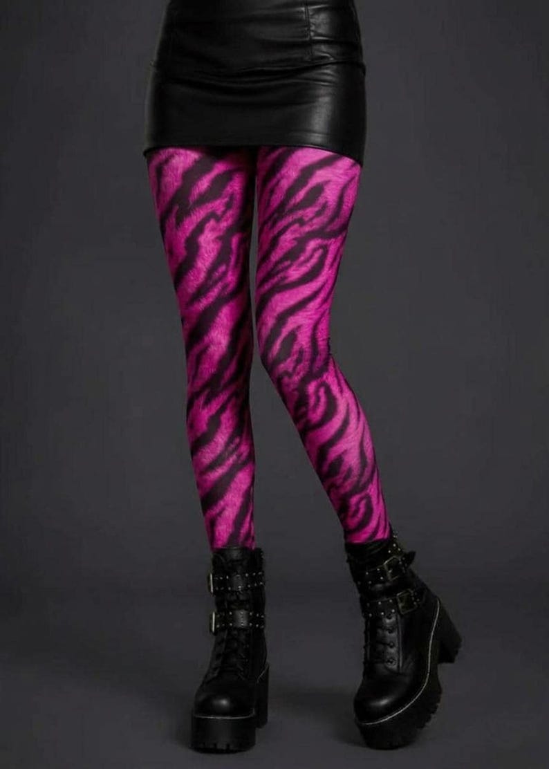 A person wearing vibrant pink and black tiger stripe leggings, a black miniskirt, and black platform combat boots.