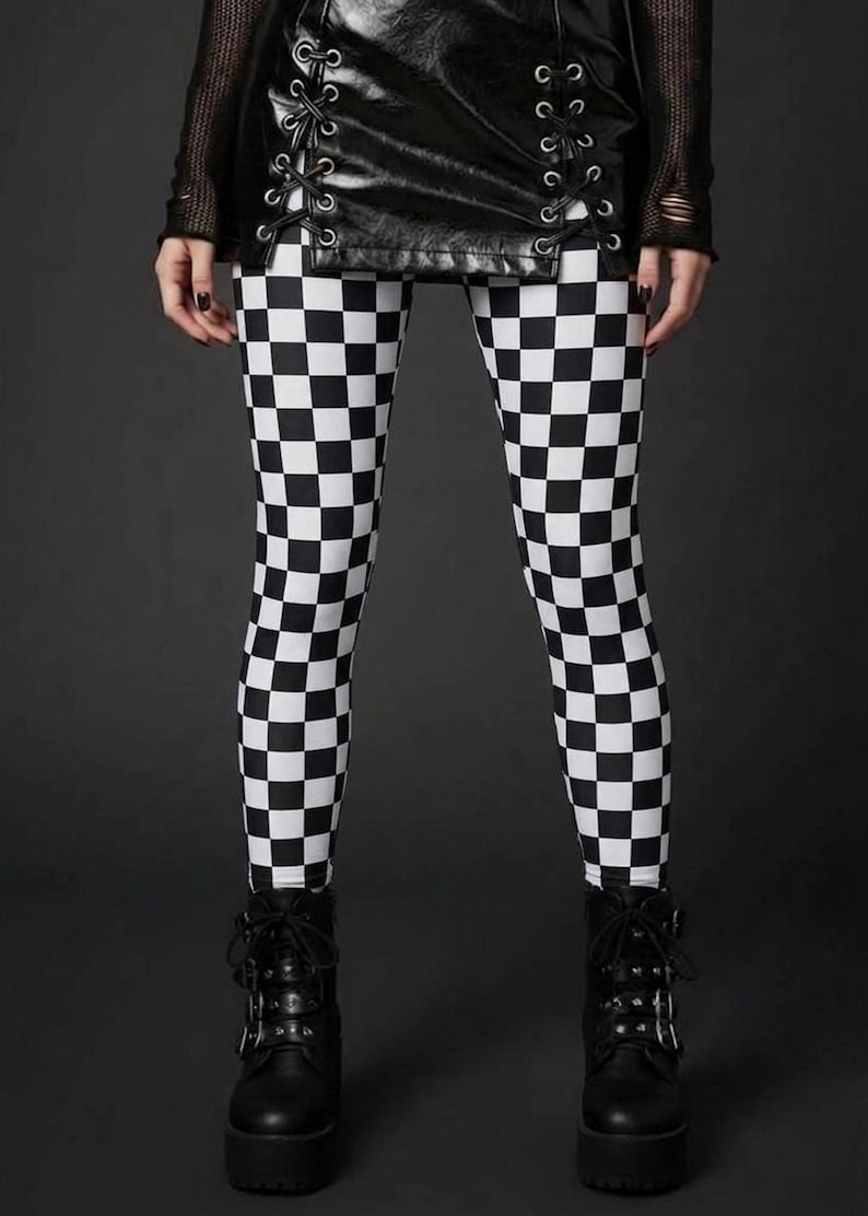 A person wearing black and white checkerboard leggings, a laced black leather mini skirt, and black platform boots.