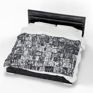 A Misfits-themed blanket with black and white band imagery is draped over a bed with a black headboard and white sheets.