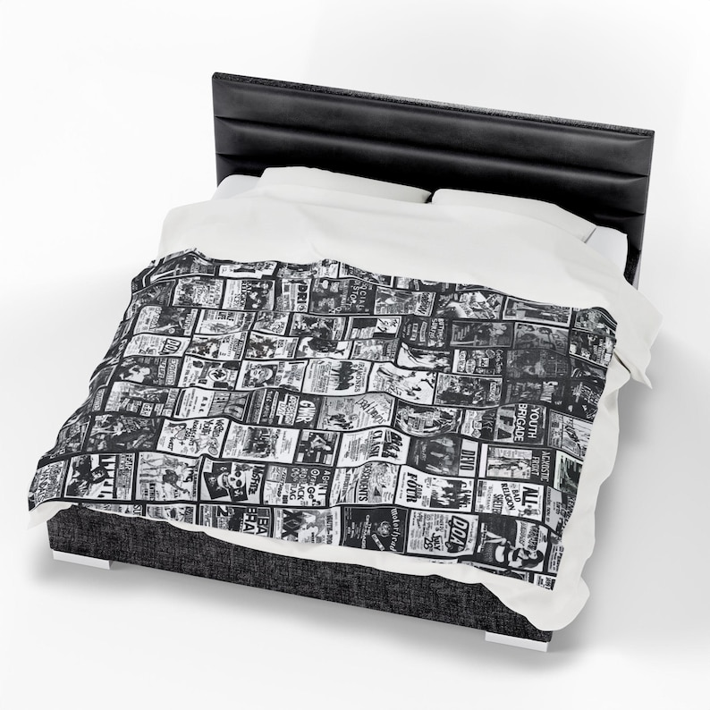 A Misfits-themed blanket with black and white band imagery is draped over a bed with a black headboard and white sheets.