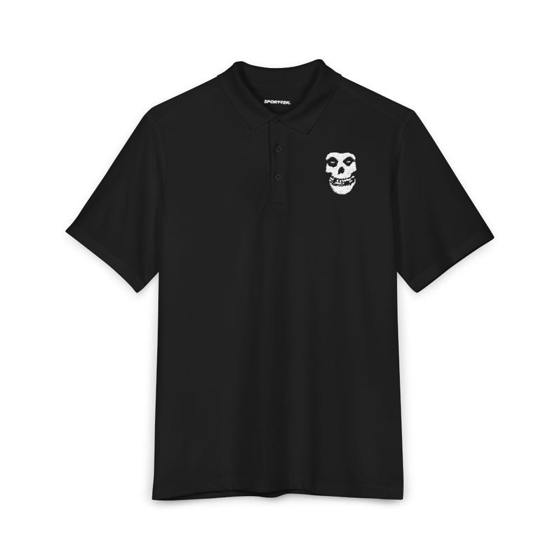 A black short-sleeved polo shirt laid flat on a white surface, featuring a white embroidered skull emblem on the left chest.