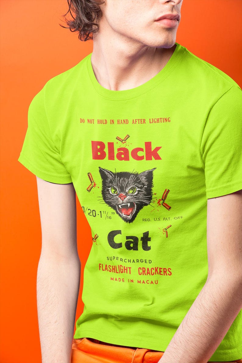 May include: A lime green t-shirt with a graphic of a black cat and the text "Black Cat". The design includes the text "Do Not Hold In Hand After Lighting" and "Flashlight Crackers". The shirt is made in Macau.