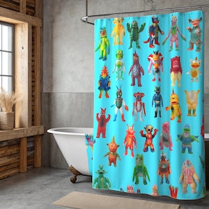 Puede incluir: Una cortina de ducha turquesa con un patrón repetido de figuras de monstruos de dibujos animados coloridos. Los monstruos son de varios colores, incluyendo rojo, verde, amarillo y azul. La cortina está en un baño con una bañera blanca.
