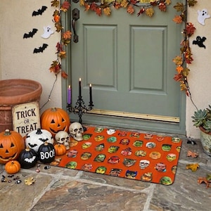 May include: A rectangular orange doormat featuring a repeating pattern of various colorful monster and character faces. The mat is placed in front of a green door decorated with autumn leaves, paper bats, ghosts, pumpkins, and a candelabra.