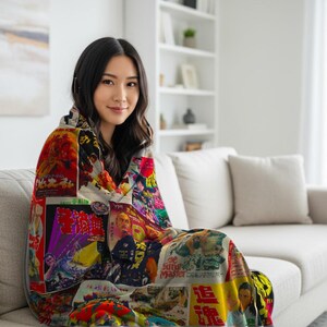 A woman sits on a light-colored sofa, wrapped in a blanket patterned with a collage of vintage Kung Fu movie posters.