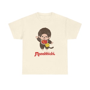 A heather cream short-sleeved t-shirt centered on a white background, printed with a Monchhichi graphic on the chest.