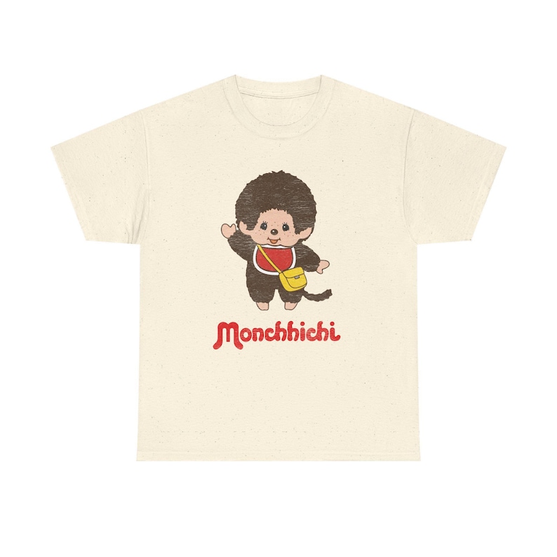 A heather cream short-sleeved t-shirt centered on a white background, printed with a Monchhichi graphic on the chest.
