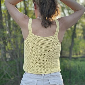 Peut inclure: Un d&eacute;bardeur en crochet jaune avec un motif carr&eacute;. Le d&eacute;bardeur est sans manches et a un col rond.