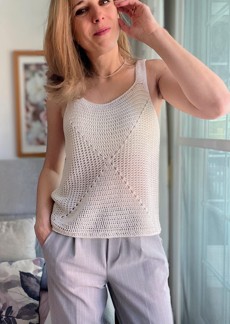 Peut inclure: Un top en crochet blanc avec un motif ajour&eacute; d&eacute;licat. Le haut est sans manches et a un col rond.