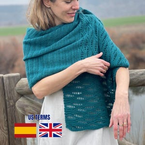Könnte beinhalten: Ein blaugrüner Häkelschal mit einem strukturierten Wellenmuster und vertikalen Rippenabschnitten. Der Schal ist über die Schultern und den Oberkörper drapiert und zeigt die komplizierte Strickarbeit sowie die tiefblau-grüne Farbe des Garns.