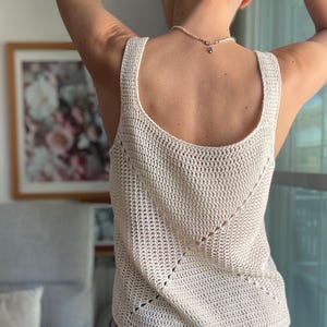 Peut inclure: Un d&eacute;bardeur en crochet blanc avec un motif ajour&eacute; d&eacute;licat. Le d&eacute;bardeur a un col rond et une coupe ample.