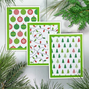 May include: Three rectangular greeting cards with bright green glitter borders. The first card features red and green Christmas ornaments. The second card displays a pattern of red and green string lights. The third card shows a pattern of red and green pine trees.