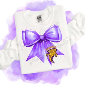May include: White sweatshirt featuring a large purple bow graphic. Below the bow is a yellow and black cartoon tornado with the text "Tornadoes". The sweatshirt has long sleeves and a crew neck.