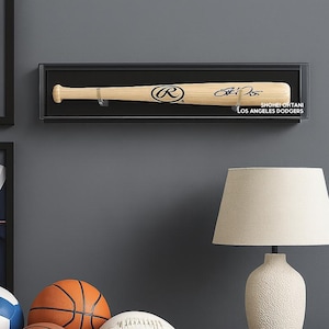 May include: A baseball bat in a black display case, with the text "Shohei Ohtani Los Angeles Dodgers". Other sports equipment includes a basketball, football, soccer ball, and a lamp.