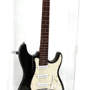 May include: Black electric guitar in a clear display case. The guitar has a white pickguard, chrome hardware, and the signature "Les Paul". The case base reads "Les Paul Rhubard Red".